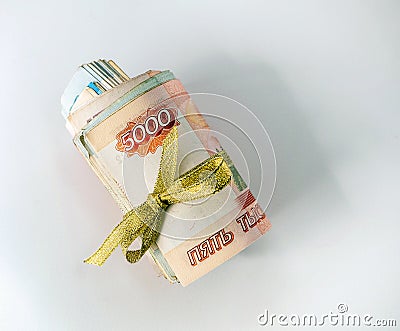 Several bills of Russian rubles are rolled up and tied with a gold ribbon. Money is located on a white background. Stock Photo