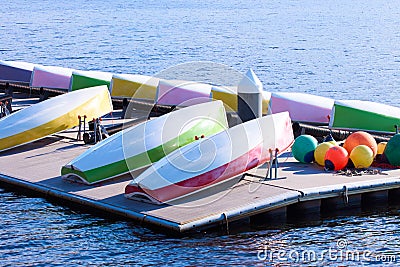 Several colourful small sailing boats demounted and overturned drying on a floating platform Stock Photo