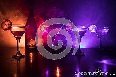 Several glasses of famous cocktail Martini, shot at a bar with dark toned foggy background and disco lights. Club drink concept. Stock Photo