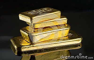 Several gold bars of different weight on a dark mirror surface Stock Photo