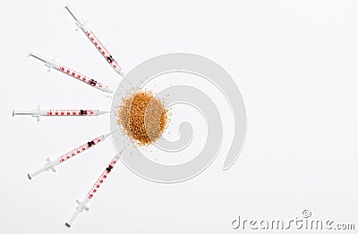 Several insulin syringes on a white background aim at a pile of cane sugar. Stock Photo