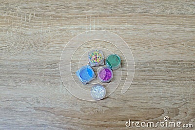 Several jars of multicolored sparkles for the design of nails or make-up on the desktop Stock Photo