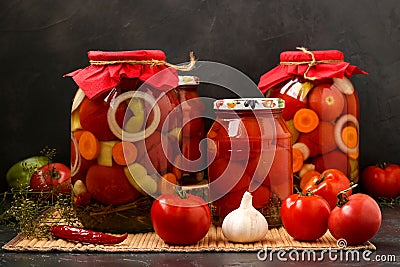 Several jars tomatoes are located on a table, on a dark background Stock Photo