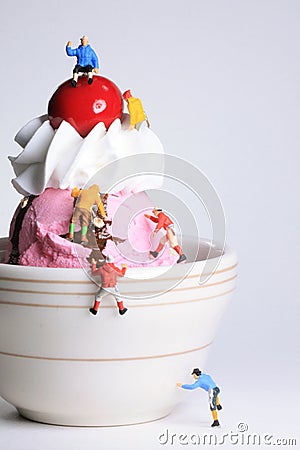 Miniature, toy climbers ascend a small bowl of ice cream. Stock Photo