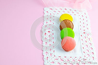 Several multicolored macaroons pastel colors on a white napkin on pink background Stock Photo