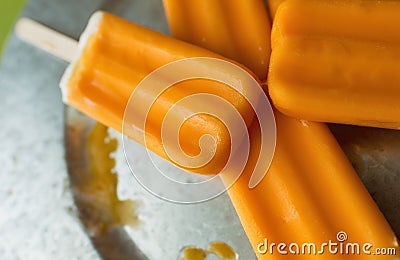 Several orange creamsicles on a galvanized steel plate. Close up view. Stock Photo