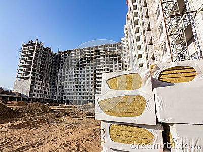 Several packs of insulation material for the walls were prepared for installation on the background of a high-rise building under Stock Photo