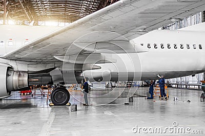 Several people wash the aircraft in the hangar for maintenance, view of the chassis, wing and tail. Editorial Stock Photo