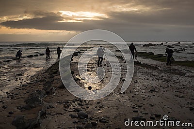 Several photographers `fish` photos on the rocky beach at sunset Stock Photo