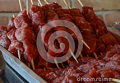 Several pieces of beef, chopped into cubes, seasoned with salt, garlic, pepper, skewered on wooden skewers, placed inside an Stock Photo