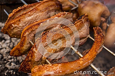 Several pieces of Liempo, or pork belly skewered on a spit and roasted on an oven at a roadside restaurant Stock Photo