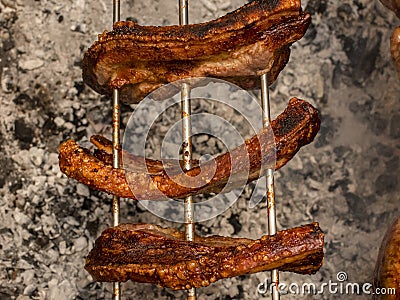 Several pieces of Liempo, or pork belly skewered on a spit and roasted on an oven at a roadside restaurant Stock Photo