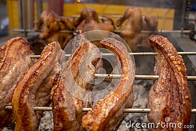 Several pieces of Liempo, or pork belly skewered on a spit and roasted on an oven at a roadside restaurant. Lechon manok in the Stock Photo