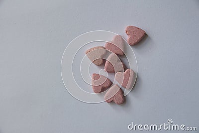 Several pink heart-shaped Vitamins lie on a white background Stock Photo