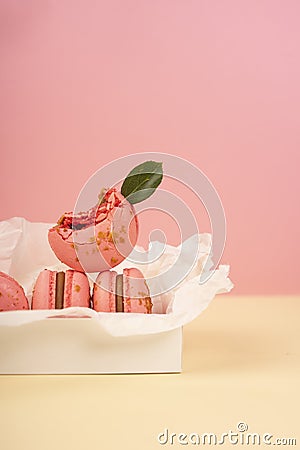 Several pink macaroons cakes one of which is bitten and decorate Stock Photo