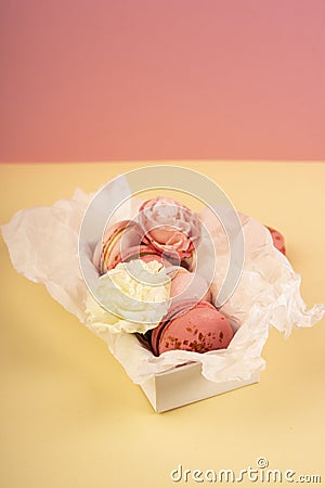 Several pink macaroons cakes one of which is bitten are placed i Stock Photo