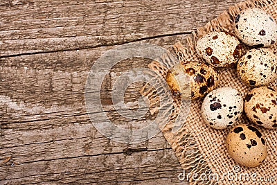 Several quail eggs on burlap on old wooden background with copy space for your text. Top view Stock Photo