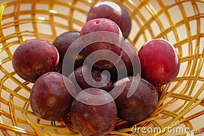 Several ripe plum lie in a braided tray Stock Photo
