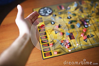 Several rolling red dice fall on a table with boardgame. Gameplay moments Stock Photo