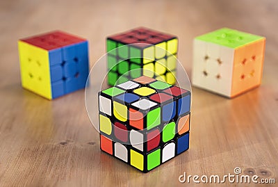 Budapest, Hungary; 9 february 2019: Several Rubik cubes intelligence toys unsolved, in a wood table Editorial Stock Photo