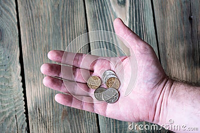 Several Russian metal rubles lie in a man`s hand over a wooden t Stock Photo