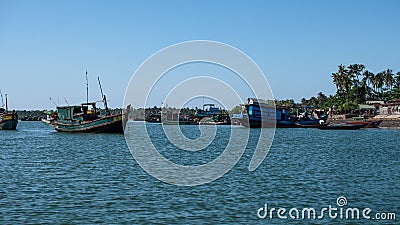 Several traditional wooden boats and houses on the shore of Chaung Thar, Myanmar Stock Photo