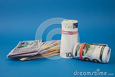 several wads of money of different currencies on a blue background Stock Photo