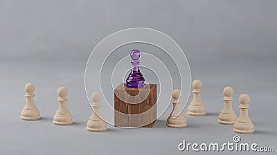 Several wooden chess pawns are surrounding another purple chess piece standing on a wooden block, a leadership concept in an Stock Photo