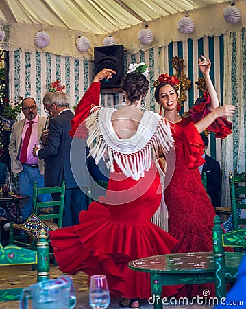 Young and beautiful women wearing flamenco dresses and dancing `Sevillanas` at the April Fair, Seville Fair Feria de Sevilla. Editorial Stock Photo