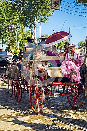 Beautiful woman in traditional and colorful dress travelling in a horse drawn carriages at the April Fair, Seville Fair Editorial Stock Photo