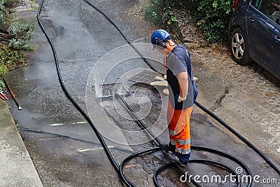 sewer cleaning and worker with water and hose in pipe Editorial Stock Photo