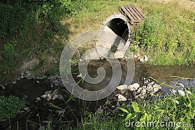 Sewer, drainpipe of concrete leads dirty water in a small brook Stock Photo