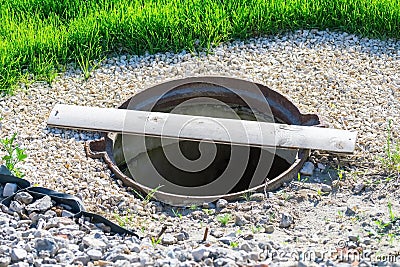 The sewer manhole without a lid is covered with one thin board Stock Photo