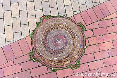 Sewer metal round hatch on the cobblestone sidewalk Stock Photo