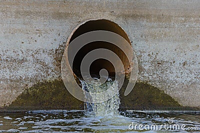 Sewer water spills out of an rusty pipe Stock Photo