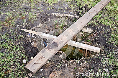 Sewer well closed by boards in violation of safety regulations Stock Photo