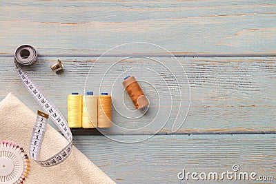 Sewing accessories and fabric on a blue background. Fabric, sewing threads, needle and sewing centimeter. top view, flatlay, Stock Photo