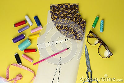 Sewing accessories and fabric on a yelow background. Sewing threads, pins, pattern and sewing centimeter. For sewing at home.Top Stock Photo