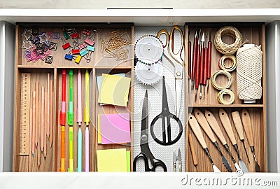 Sewing accessories and stationery in open desk drawer Stock Photo