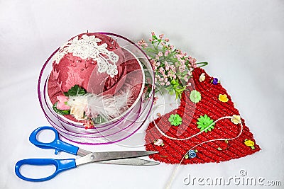 Sewing and crafts for Valentines Day - Pink hat pin cushion and sissors with ribbon and flowers and a red fabric heart Stock Photo