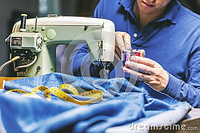 Sewing denim jeans with sewing machine. Repair jeans by sewing machine. Alteration jeans, hemming a pair of jeans, handmade Stock Photo