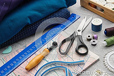 Tailoring scissors, measuring tape, spools of thread, patterns on paper, seamstress cutting knife, sewing layout, rulers, Stock Photo