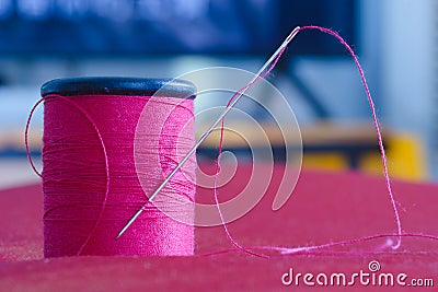 Sewing needle and pink thread roll Stock Photo