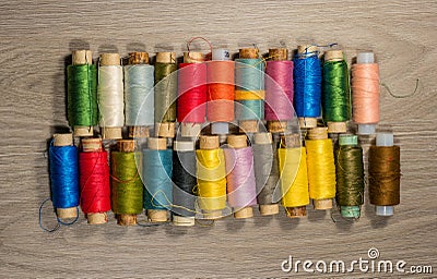 Sewing thread reels on a wood textured background. Stock Photo