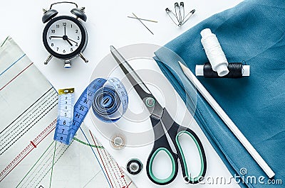 Sewing to order on time. Flat lay, top view, copy space. Blue fabric, watch, sewing tools and needlework accessories Stock Photo