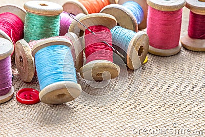 Sewing tools many different colorful thread, needle, buttons on wooden background. Stock Photo