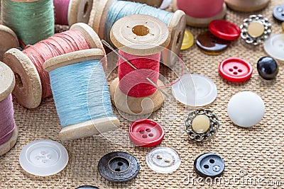 Sewing tools many different colorful thread, needle, many different buttons on wooden background. Stock Photo