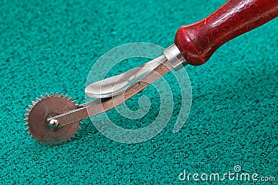 Sewing tracing wheel on green textile Stock Photo