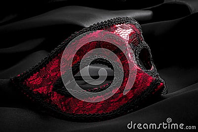 Sexuallity, sensuality and eroticism concept with close up on a beautiful red lace masquerade vintage gothic mask on black silk Stock Photo