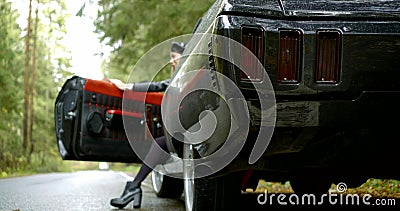 Sexual woman is sitting in expensive car with open doors, showing leg, closing door Stock Photo